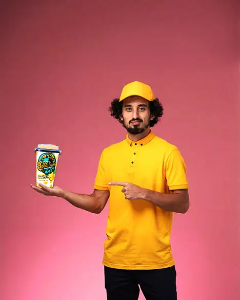 Man in yellow outfit pointing at a Bobalicious Pineapple Bubble Tea cup against a pink background.