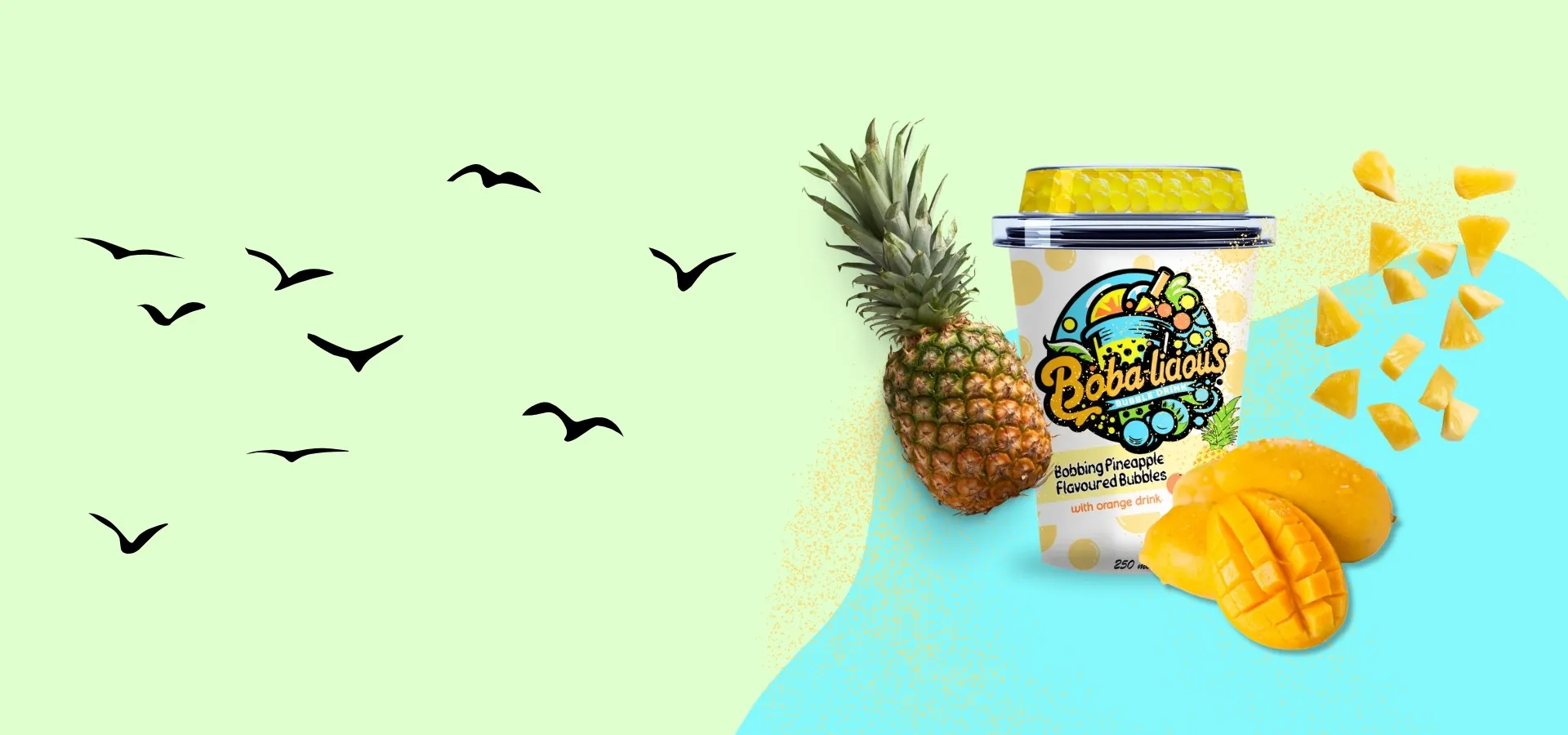 Bobalicious pineapple flavored bubbles with orange drink cup, surrounded by fresh pineapple and mango slices.